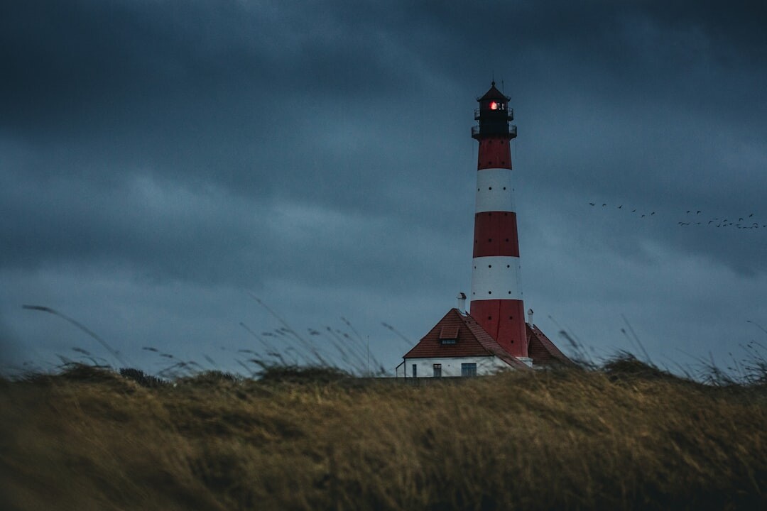 Red and white lighthouse on a windswept Danish coastal dune