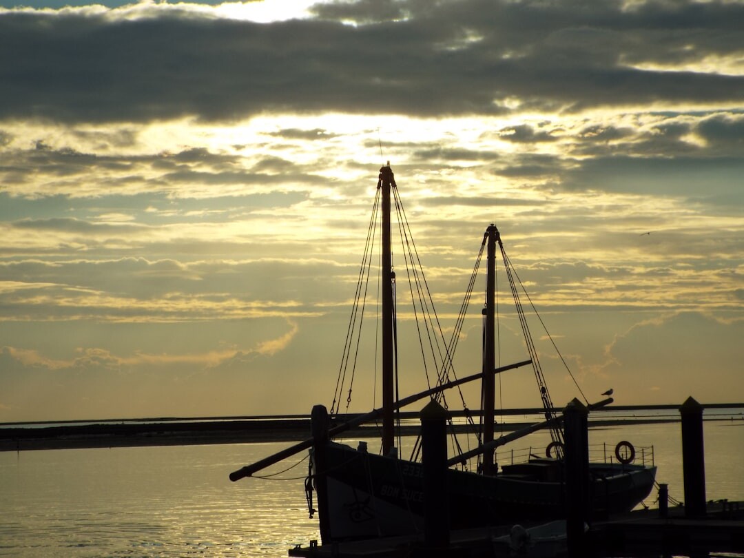 Danish coastal harbor at sunset with fishing boats silhouetted against the sky